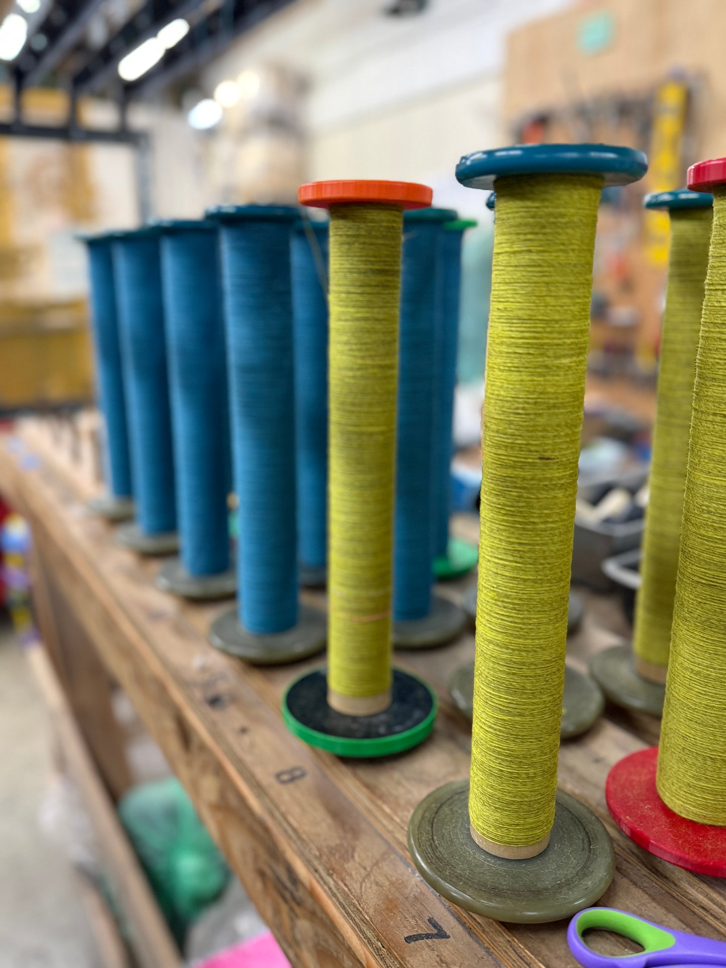 Bobbins of blue and yellow singles yarn on a shelf, waiting to be plied.