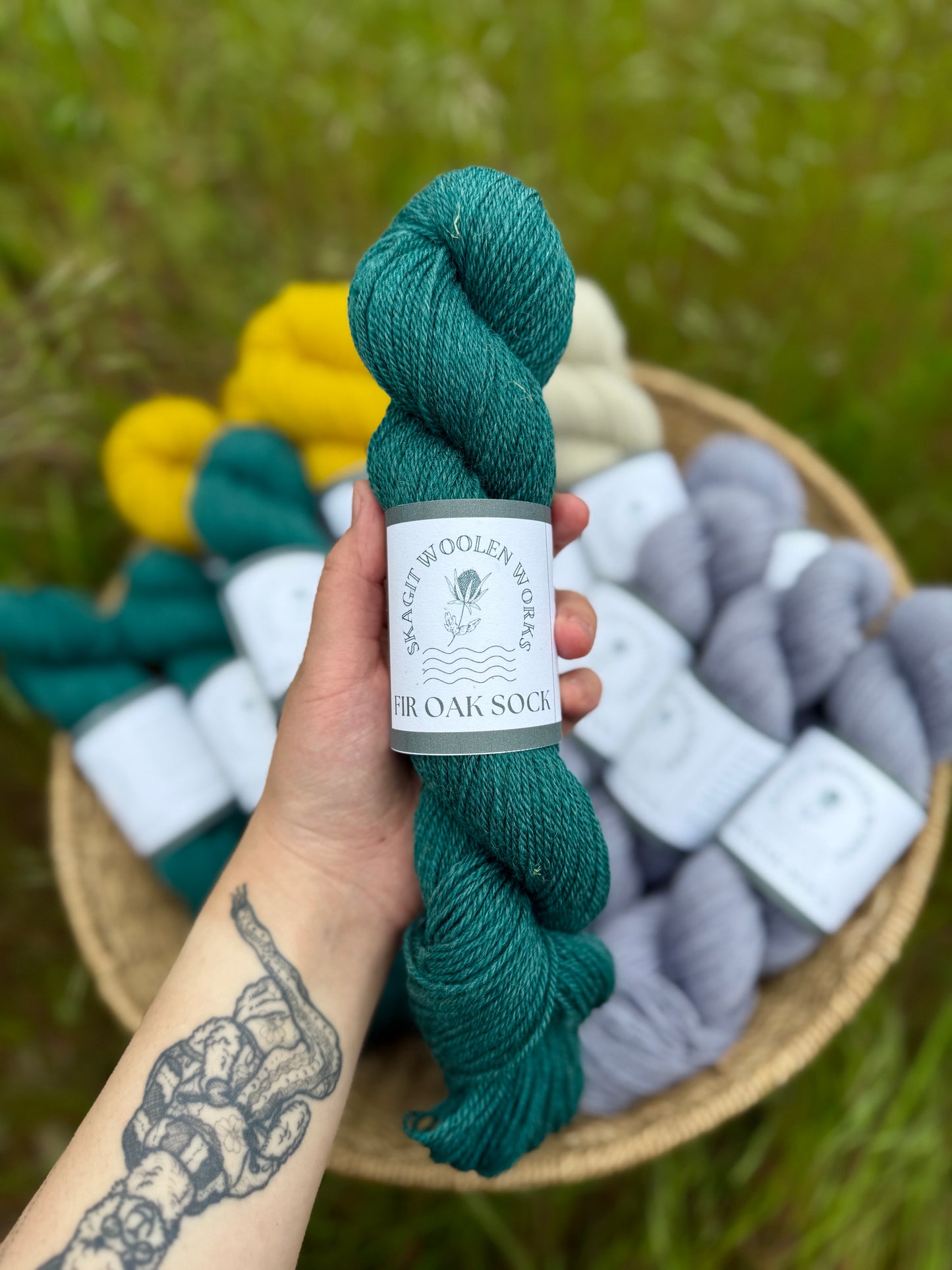 Hand holding a skein of a deep teal dyed  Romney x Suffolk sock yarn.