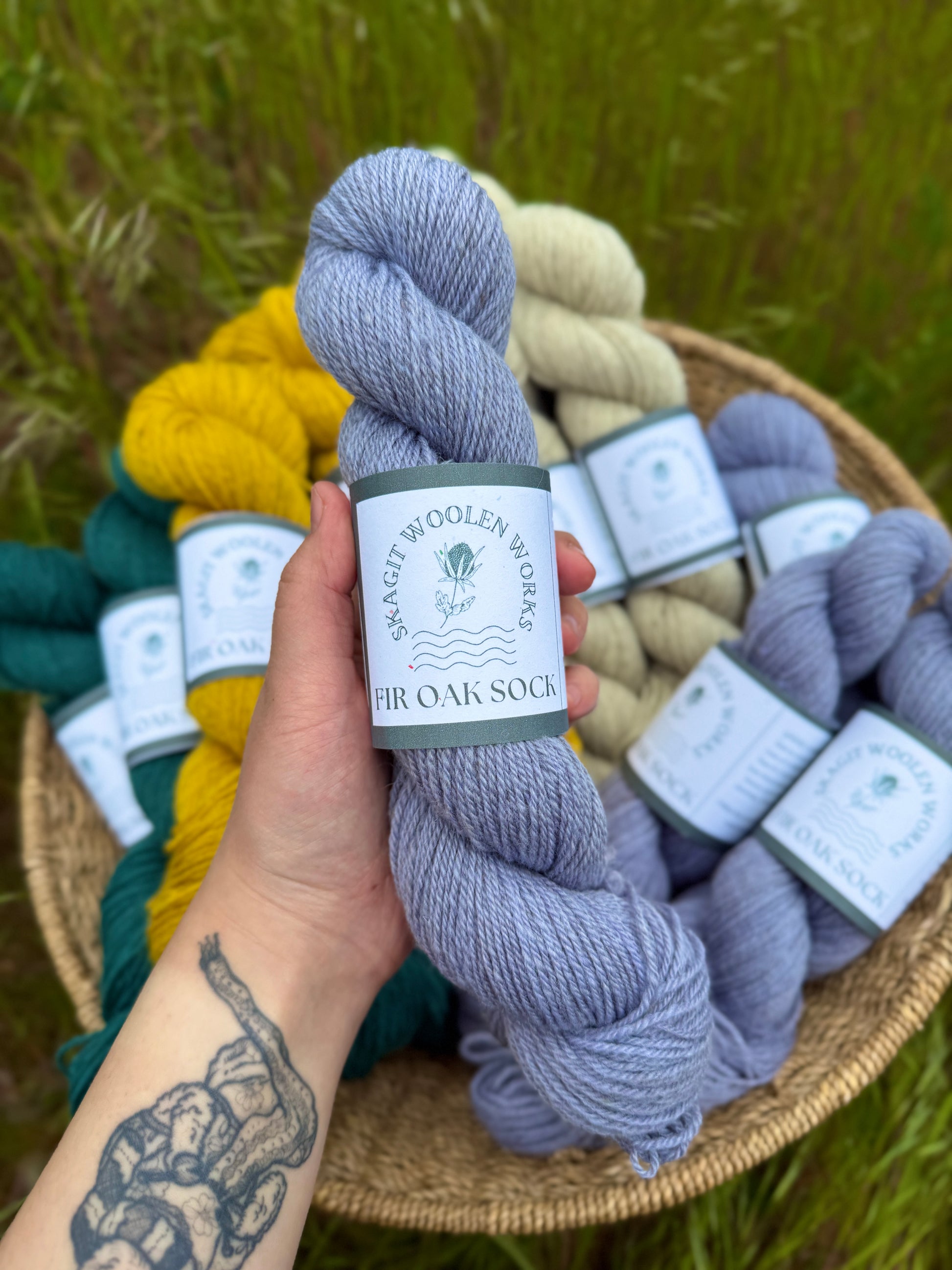 Hand holding a skein of a soft periwinkle  dyed  Romney x Suffolk sock yarn.